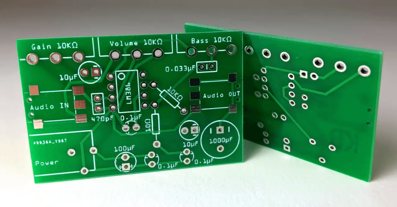 Photograph of top and bottom views of two green, populated audio amplifier PCB prototypes with resistors and an IC socket